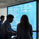 Modern office space with a group of diverse professionals collaborating around a large screen.